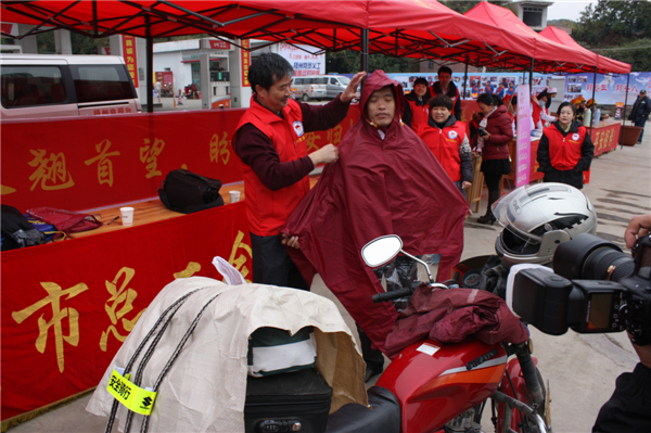 梧州市總工會的黨員義工們在市東出口春運服務站助力“摩托大軍”平安返鄉(xiāng)，幫助他們檢查車輛和行李，穿上雨衣。--黃賀峰攝.j